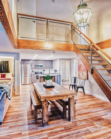 Interior living and dining room with wooden staircase and loft
