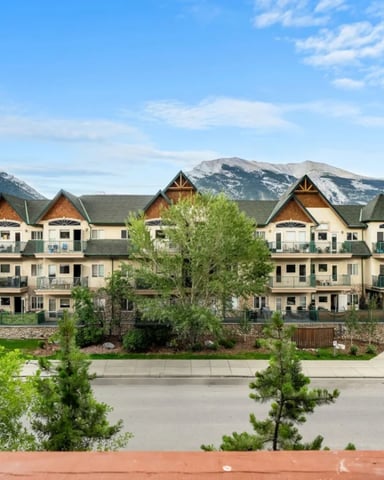 Stone and wood lodge buildings with signage for springs and hot pools, mountains visible in background