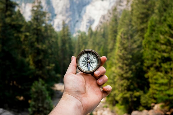 Compass held in a mountain forest — integrity and direction