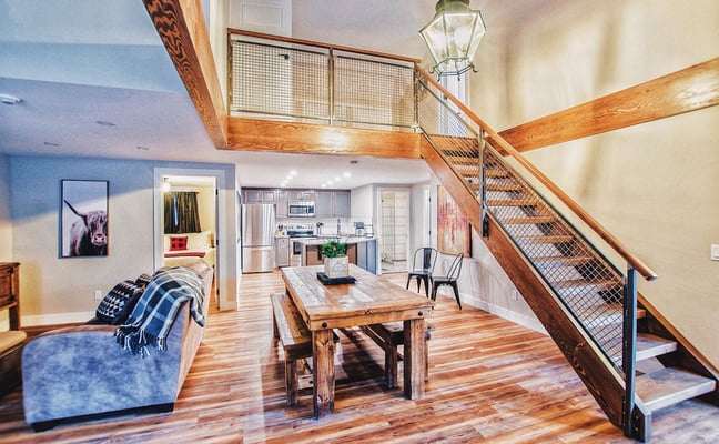 Interior living and dining room with wooden staircase and loft